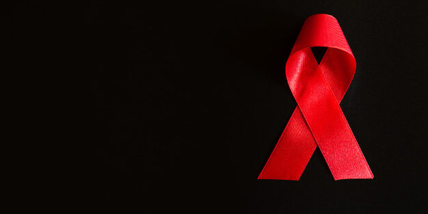 consciencia-de-fita-vermelha-closeup-em-fundo-preto-para-a-campanha-do-dia-mundial-da-aids_53476-2864